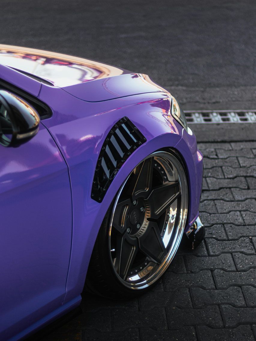 Person wearing black gloves wiping a black car door handle with a blue cloth.