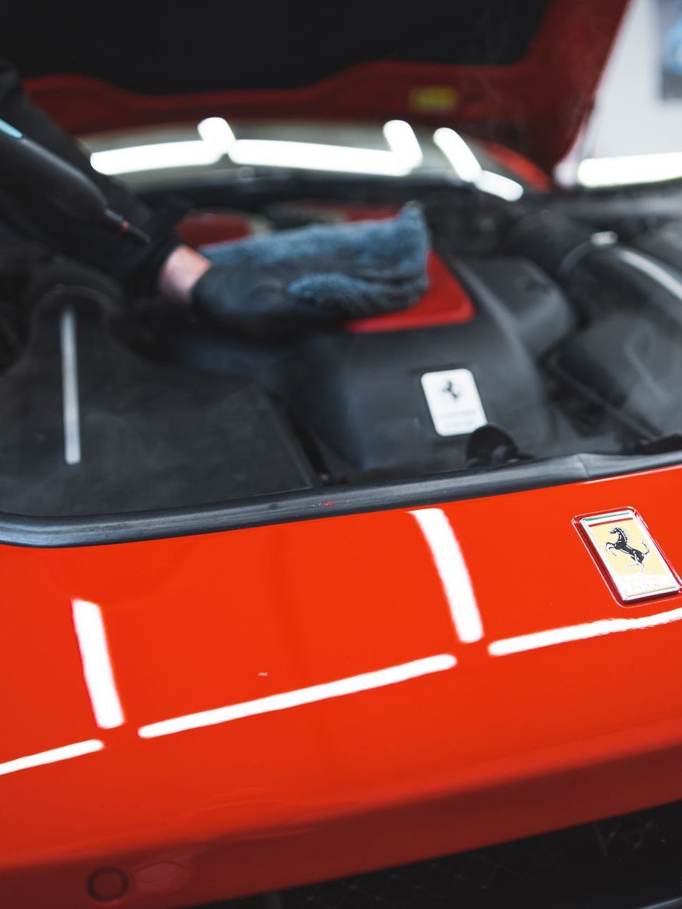 A gloved hand wipes a brown leather car seat with a white and black cloth.