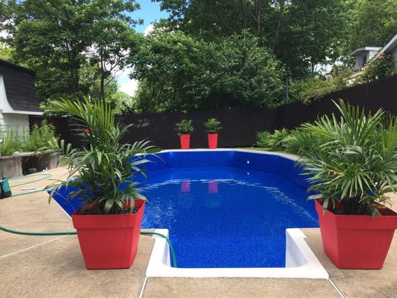 Une grande piscine est entourée d'un patio en briques et de chaises.