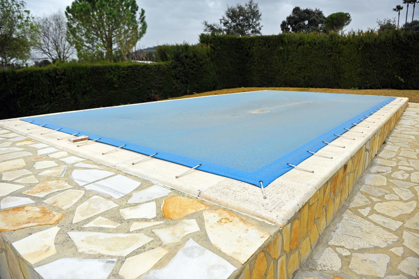 Une grande piscine est entourée d'un patio en briques et de chaises.