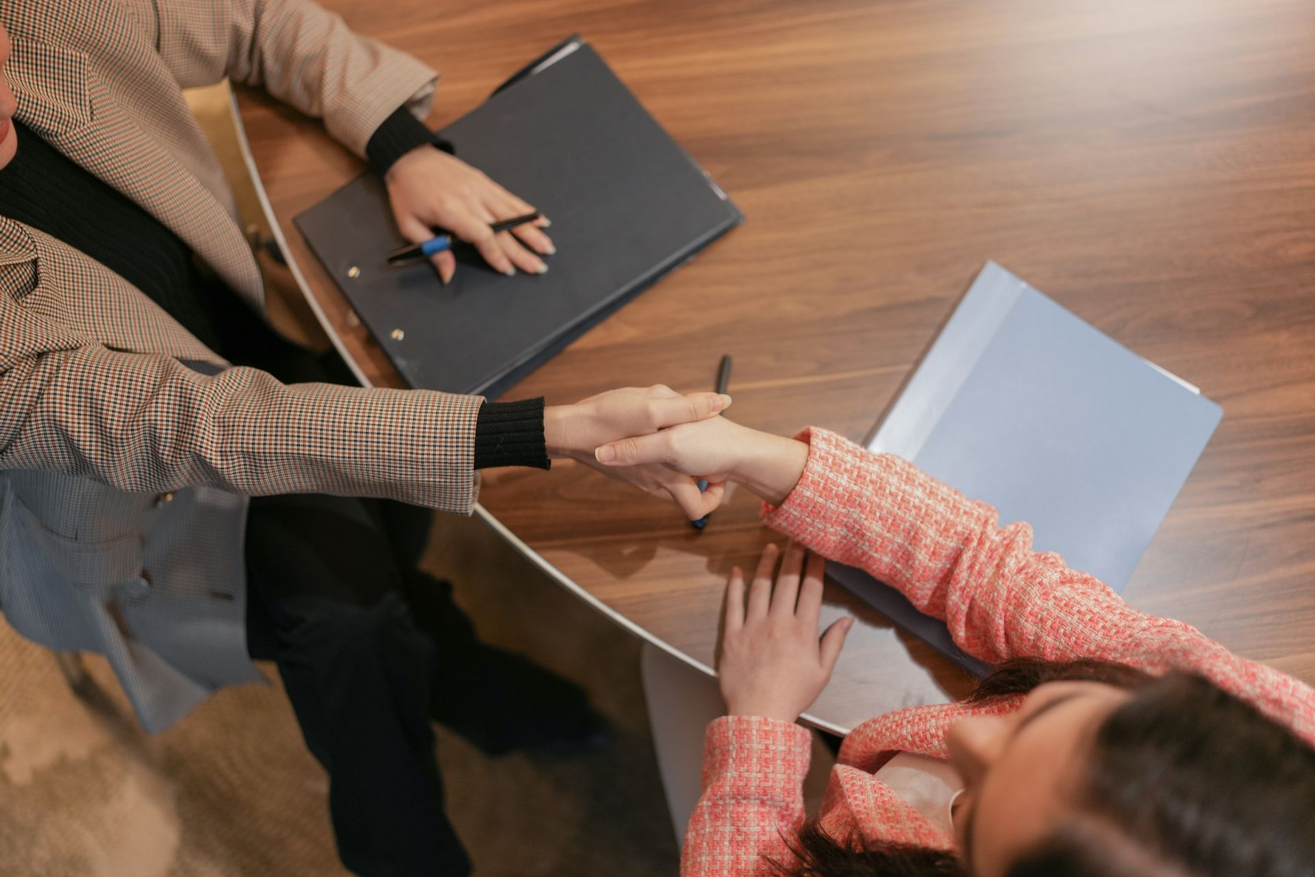 A woman is shaking hands with another woman at a table.