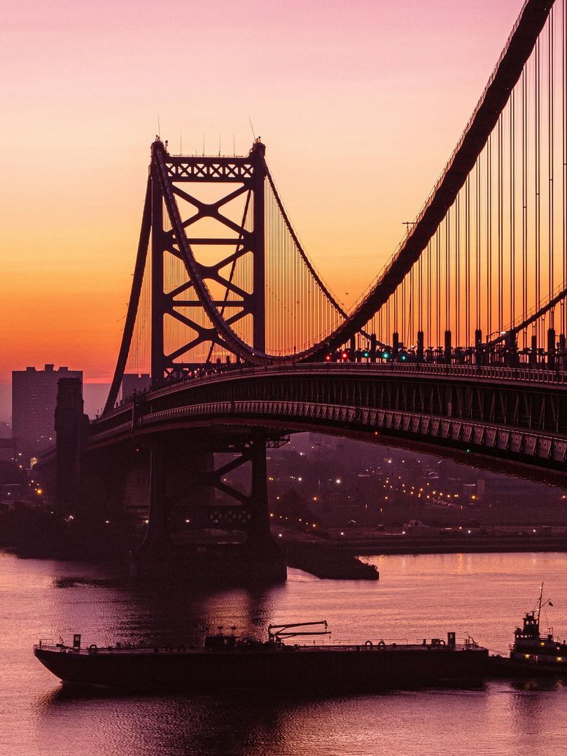 A bridge over a body of water with a sunset in the background