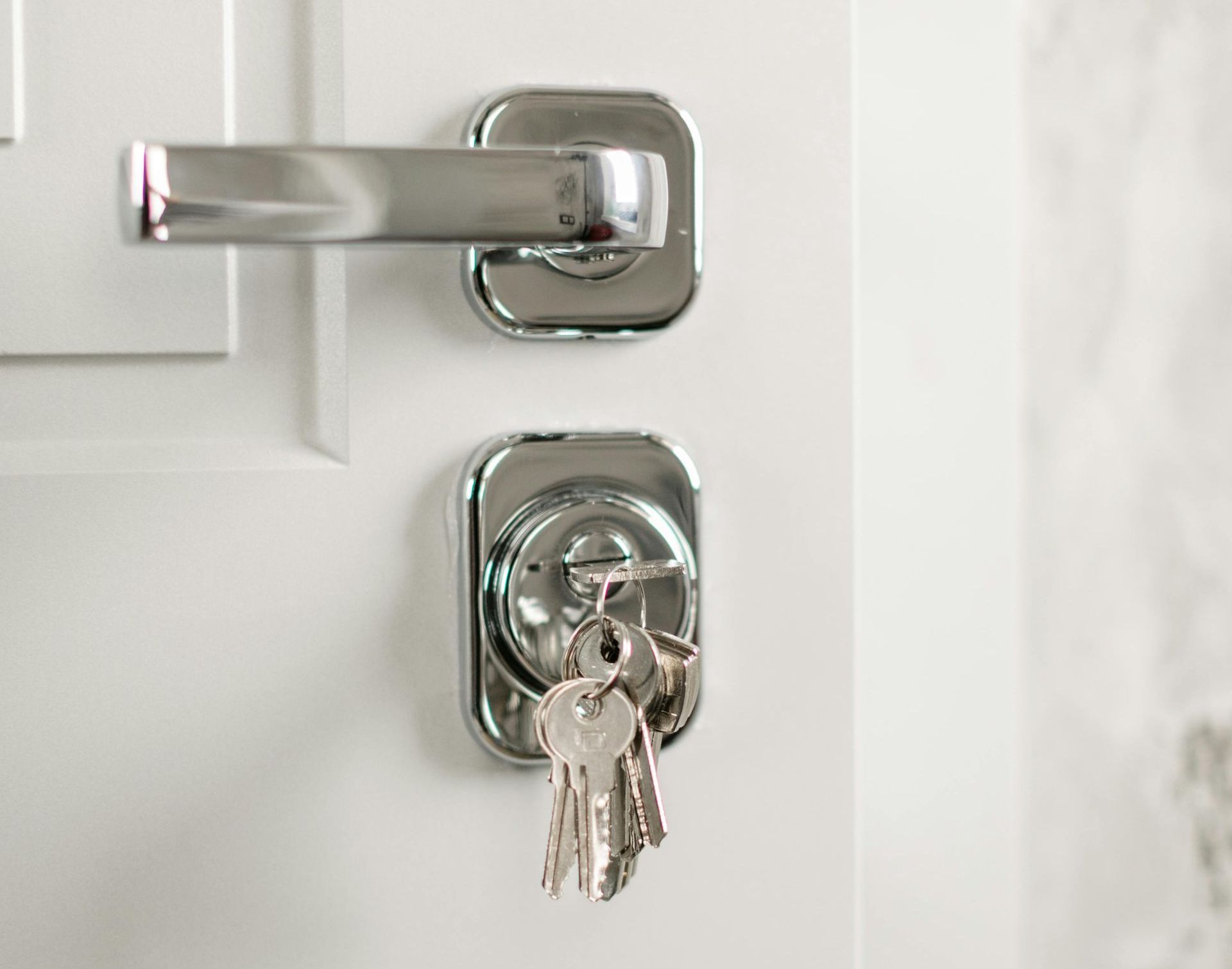 A bunch of keys are hanging from a door lock.