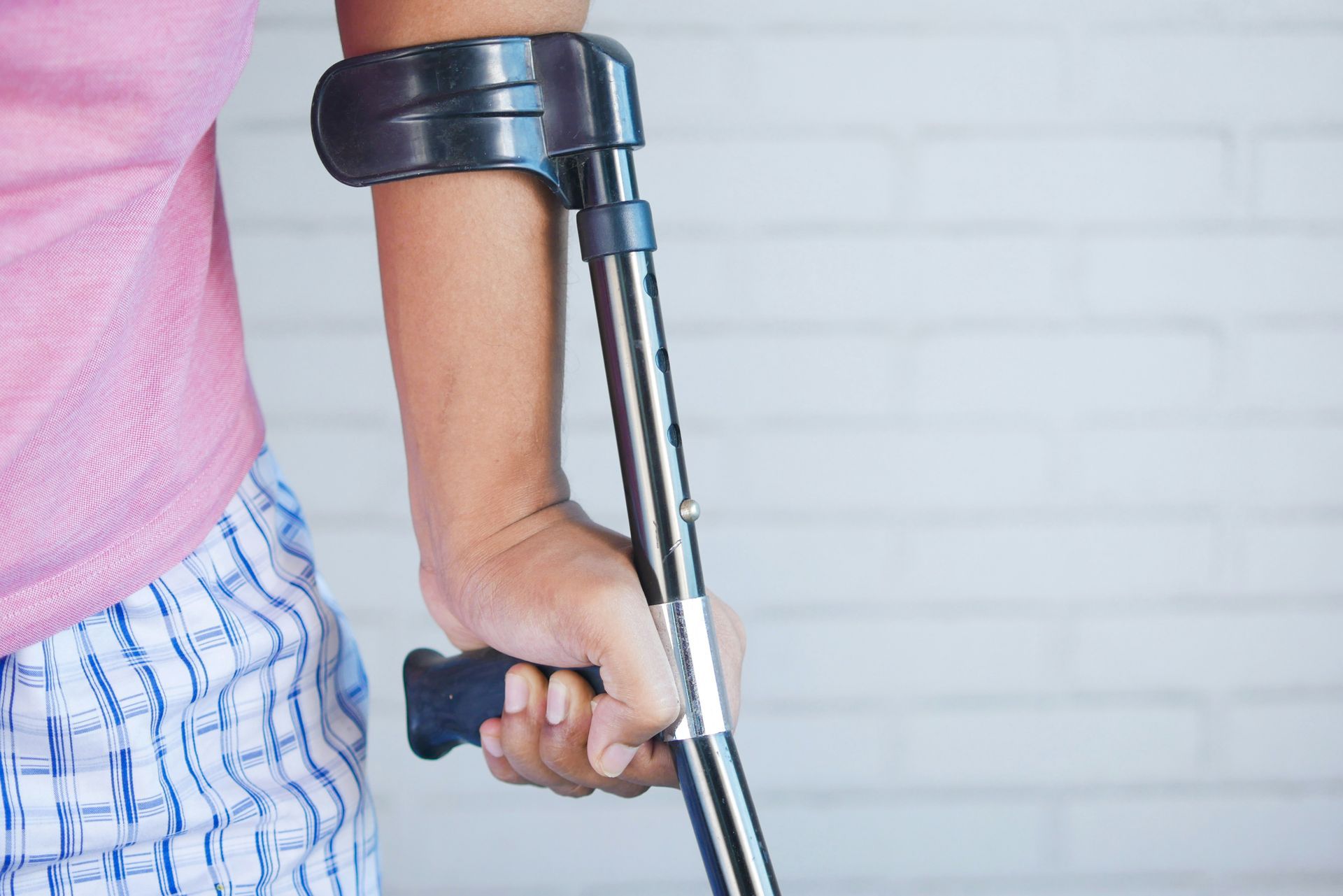 A person is holding a crutch in their hand.