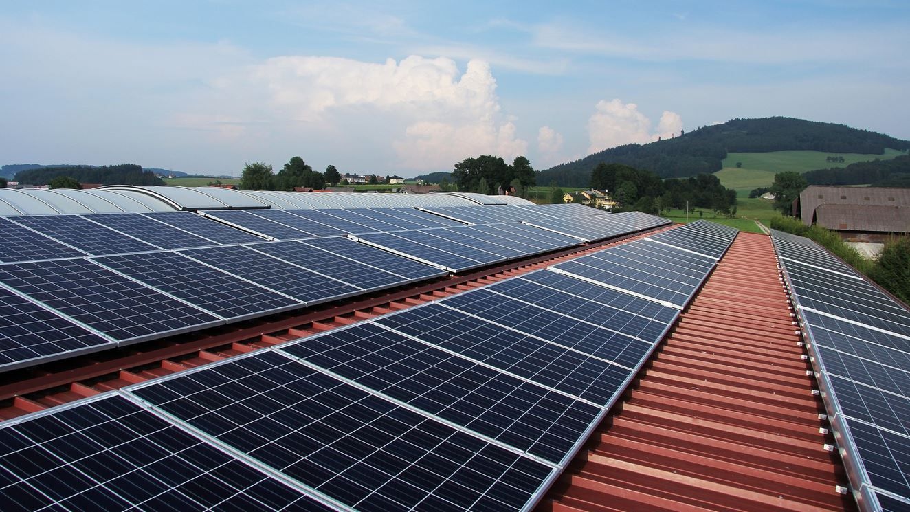 Solar panels installed on a red-tiled roof, countryside in the background.