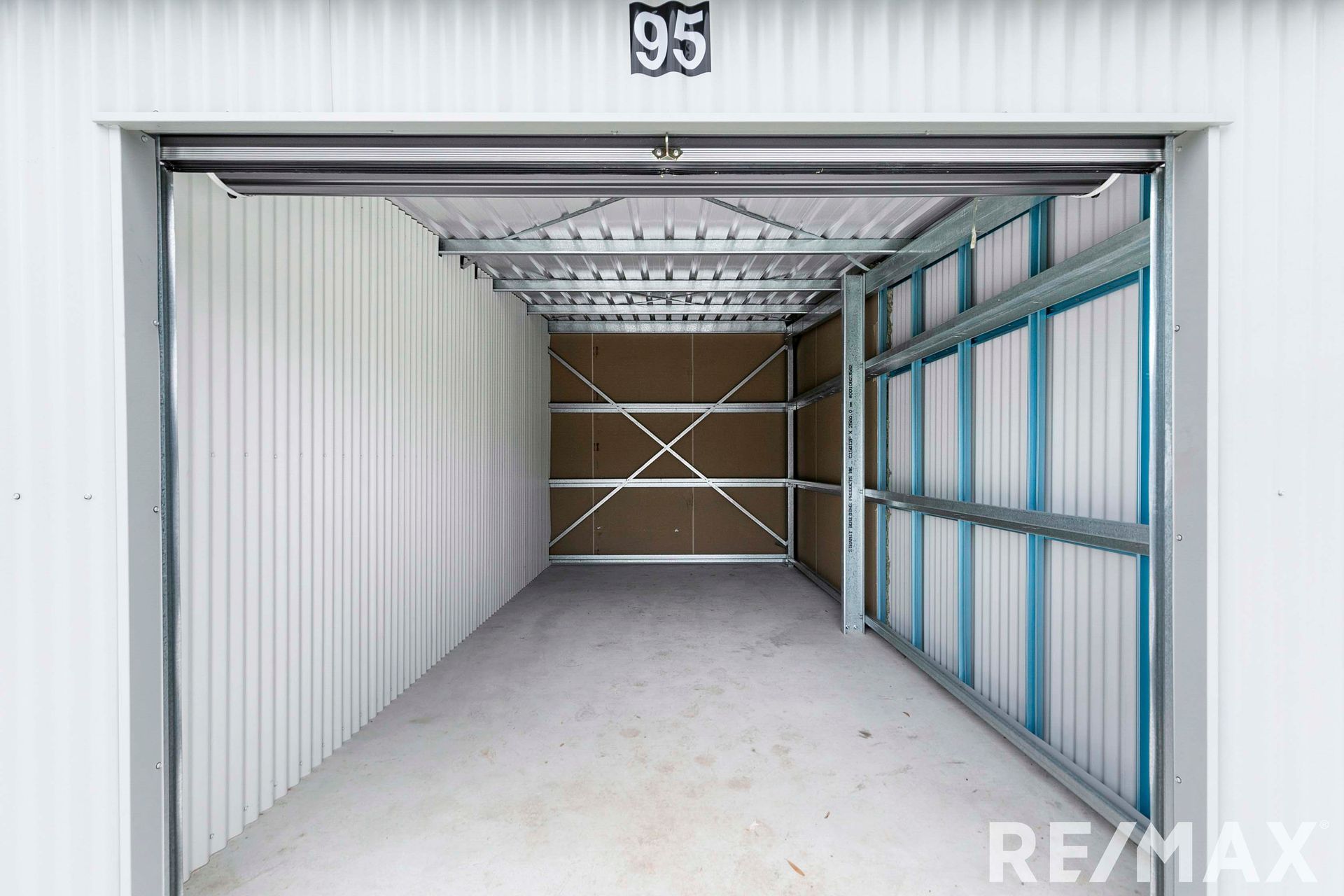 Interior of an empty, metal storage unit with an open door; unit number 95 visible.