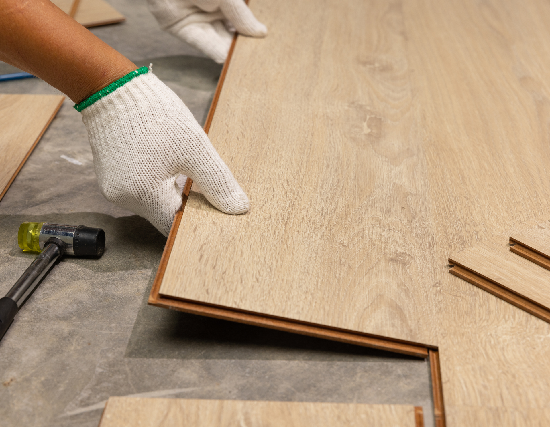A person is installing a wooden floor with a hammer.