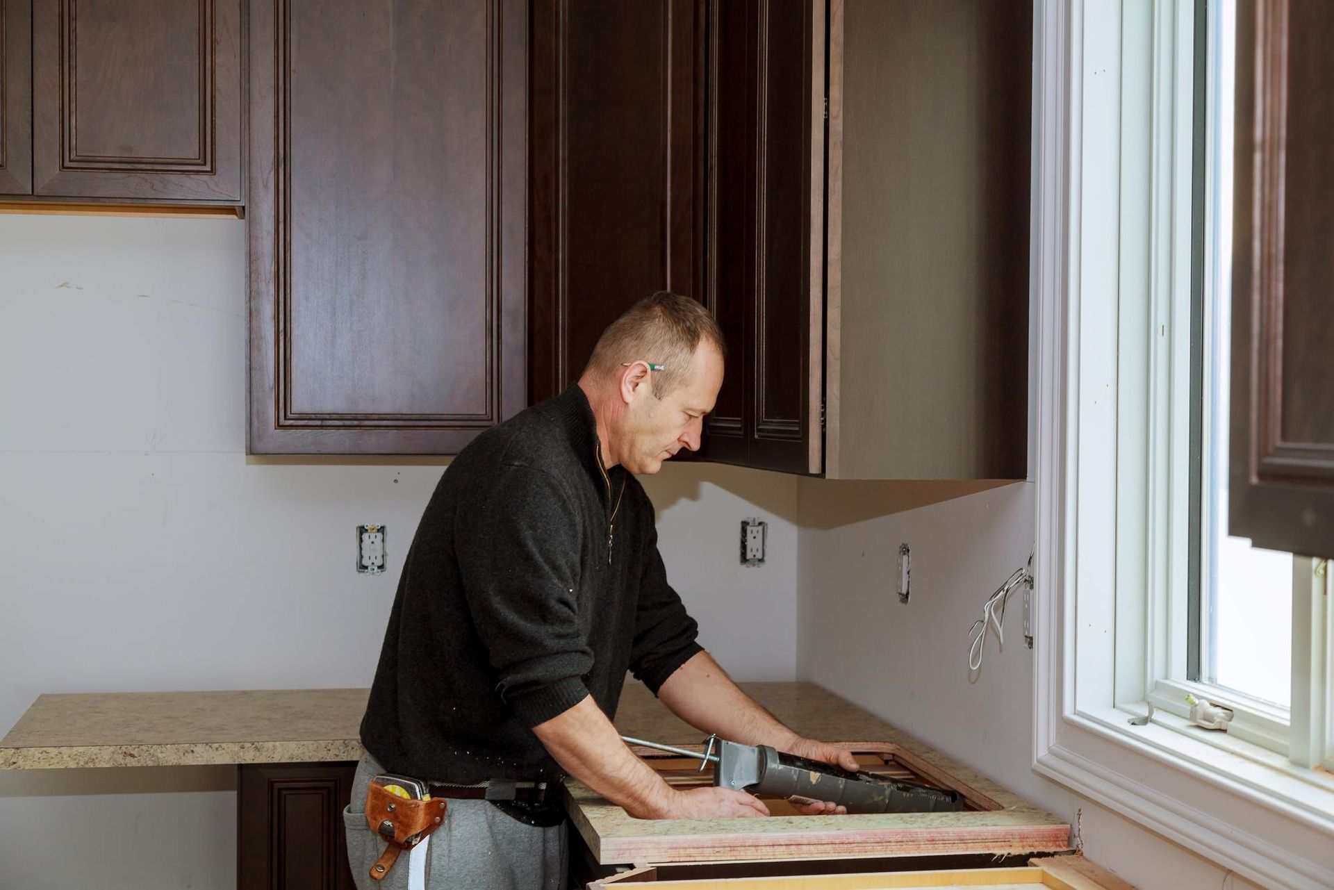 A man is working on a kitchen counter.