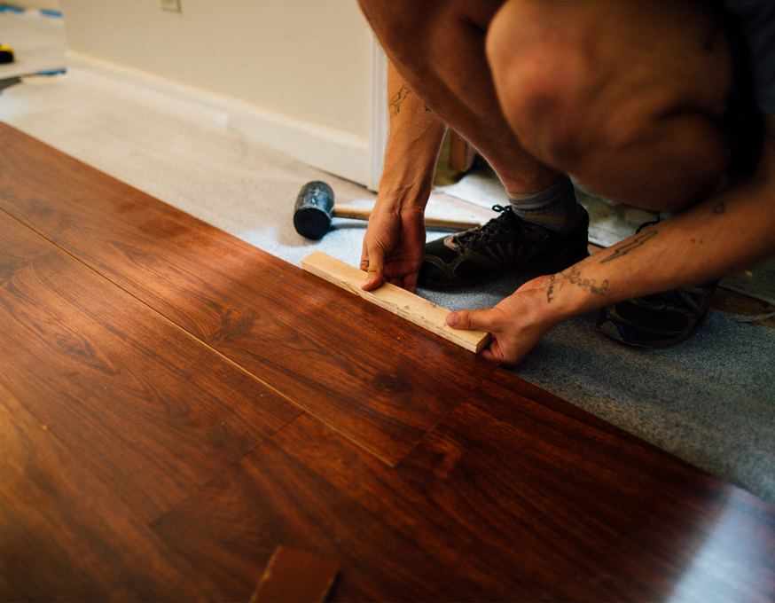 A man is measuring a piece of wood with a ruler.