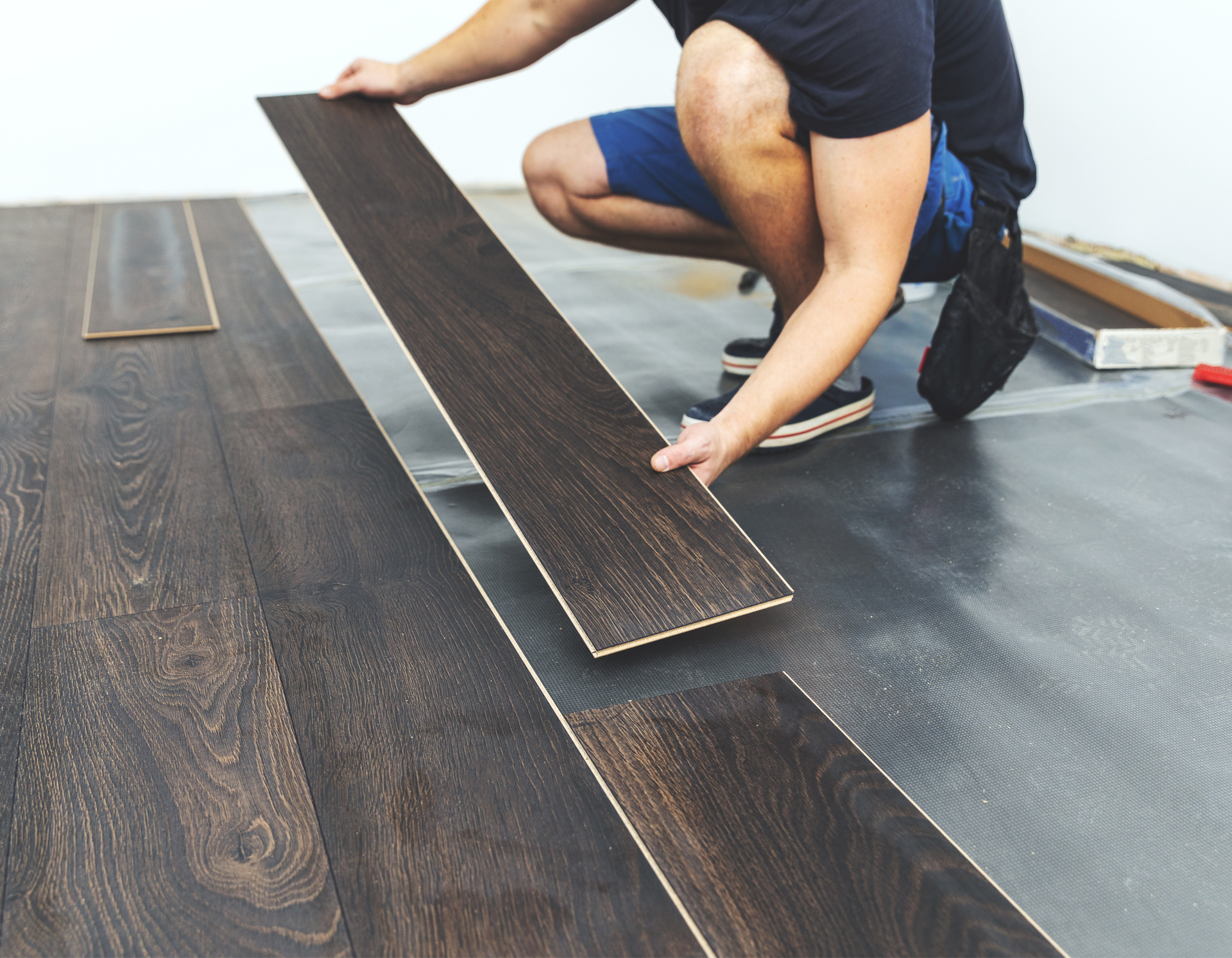 A man is installing a wooden floor in a room.