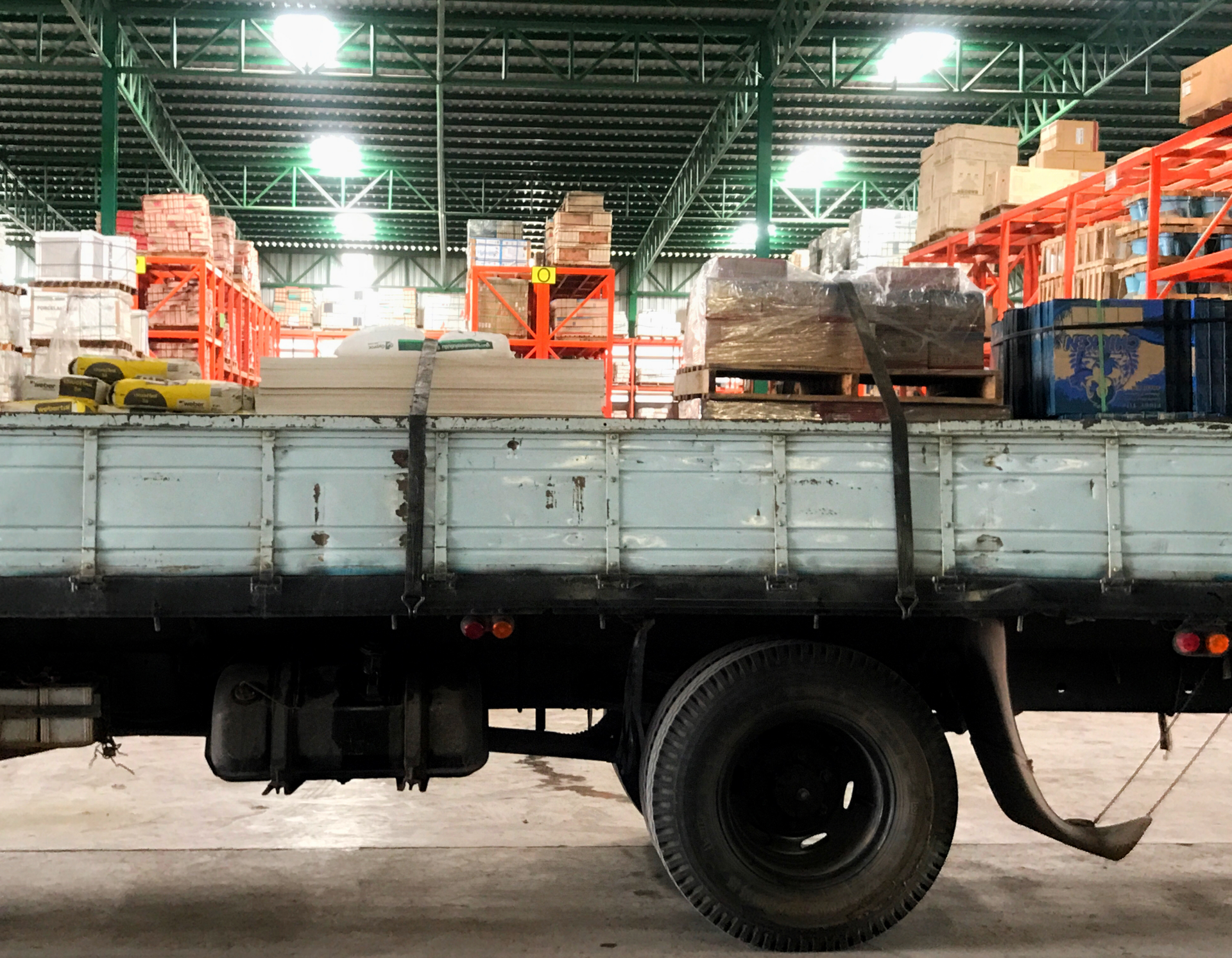 A truck is parked in a warehouse with boxes in the back
