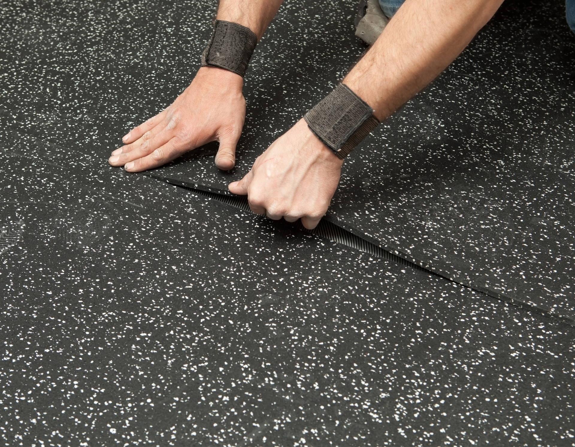 A person is laying a piece of rubber on the floor.