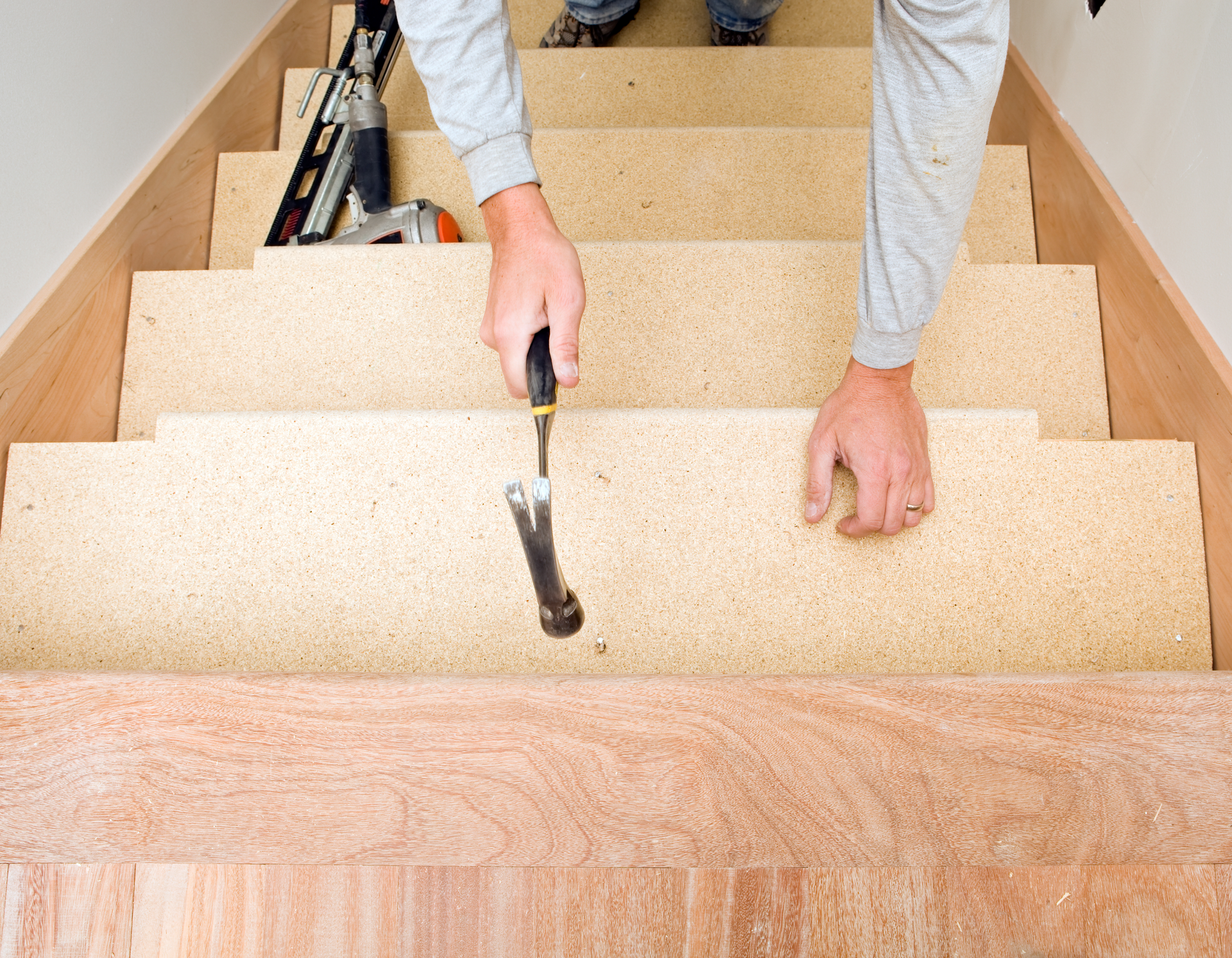A man is hammering nails into a wooden staircase
