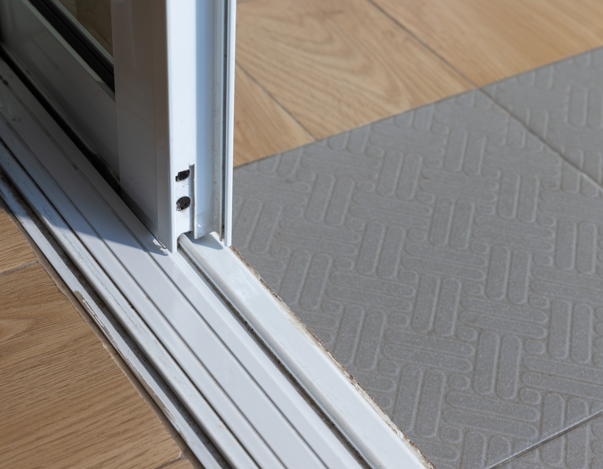A close up of a sliding glass door on a tiled floor