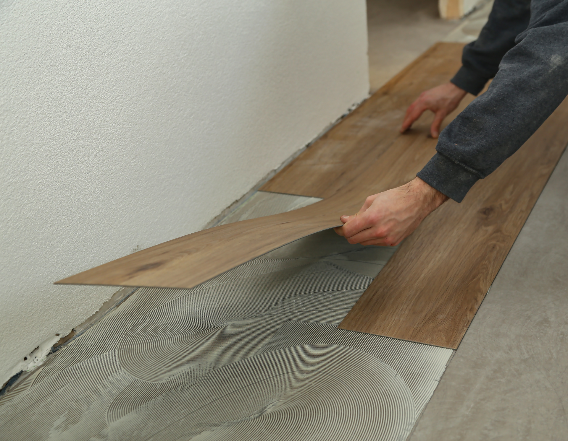 A person is installing a wooden floor in a room.