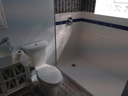 A bathroom with a toilet , sink and shower.