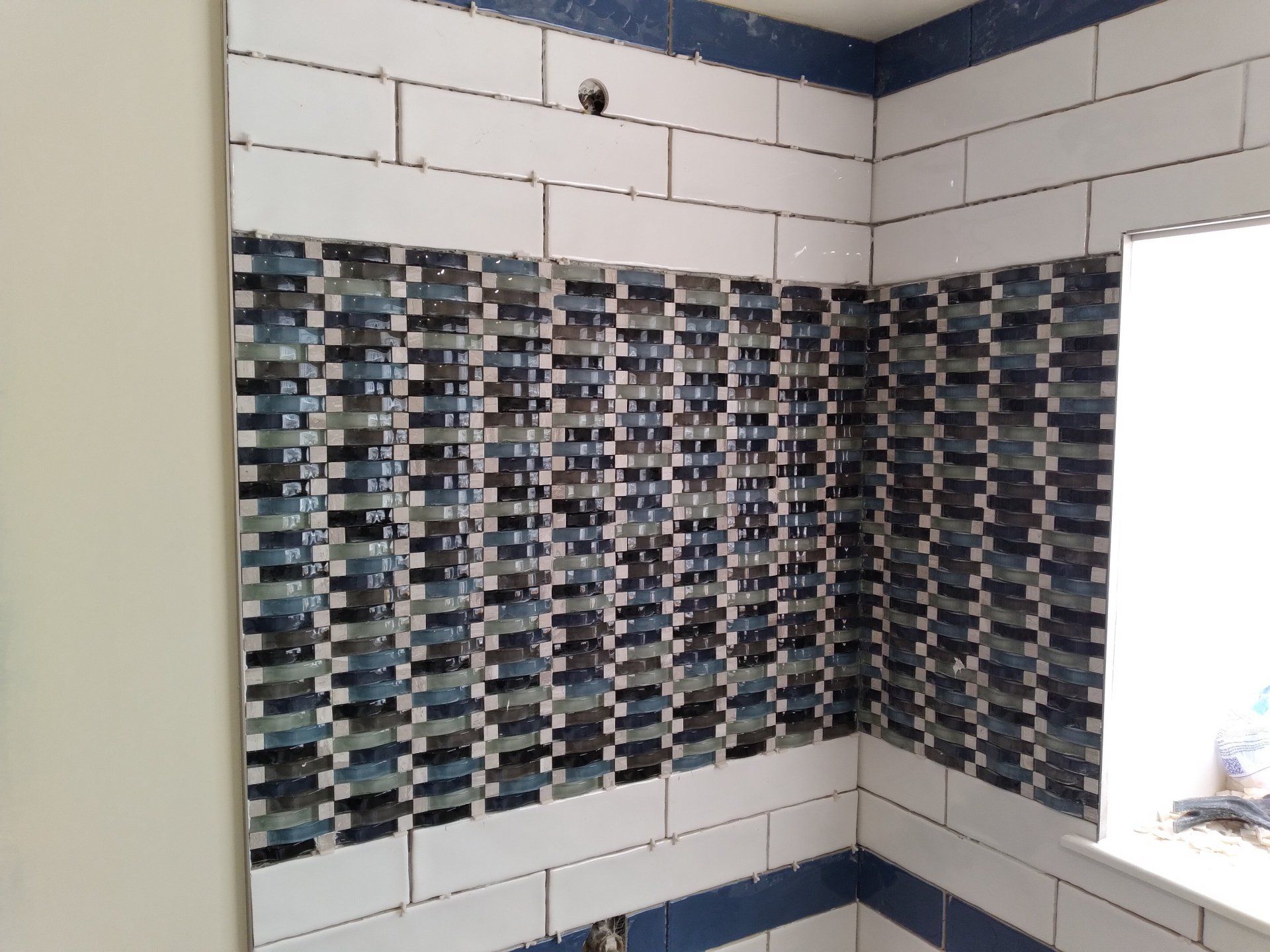 A bathroom with blue and white tiles and a window