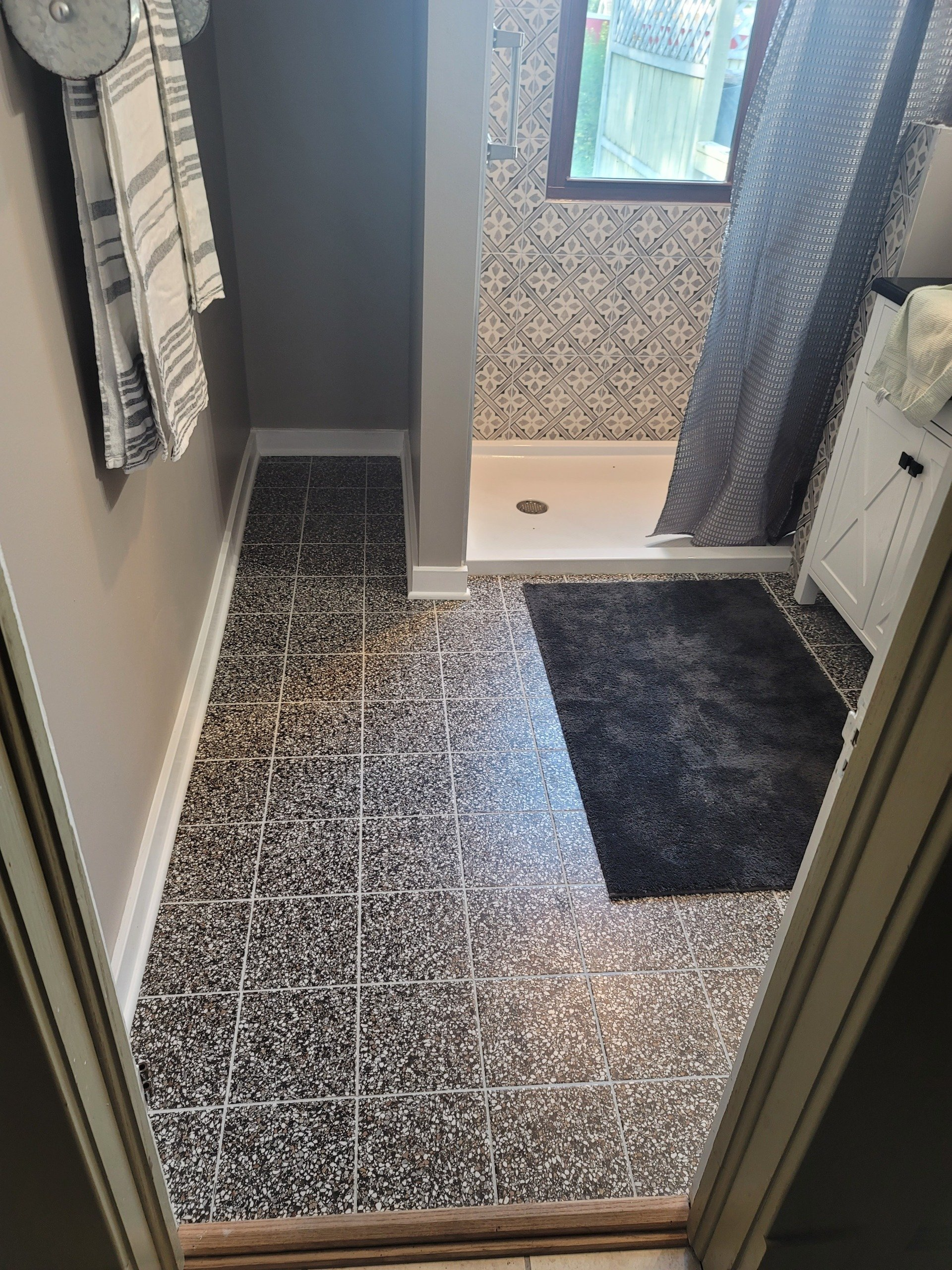 A person installing floor tiles, using leveling clips to ensure a flush finish.