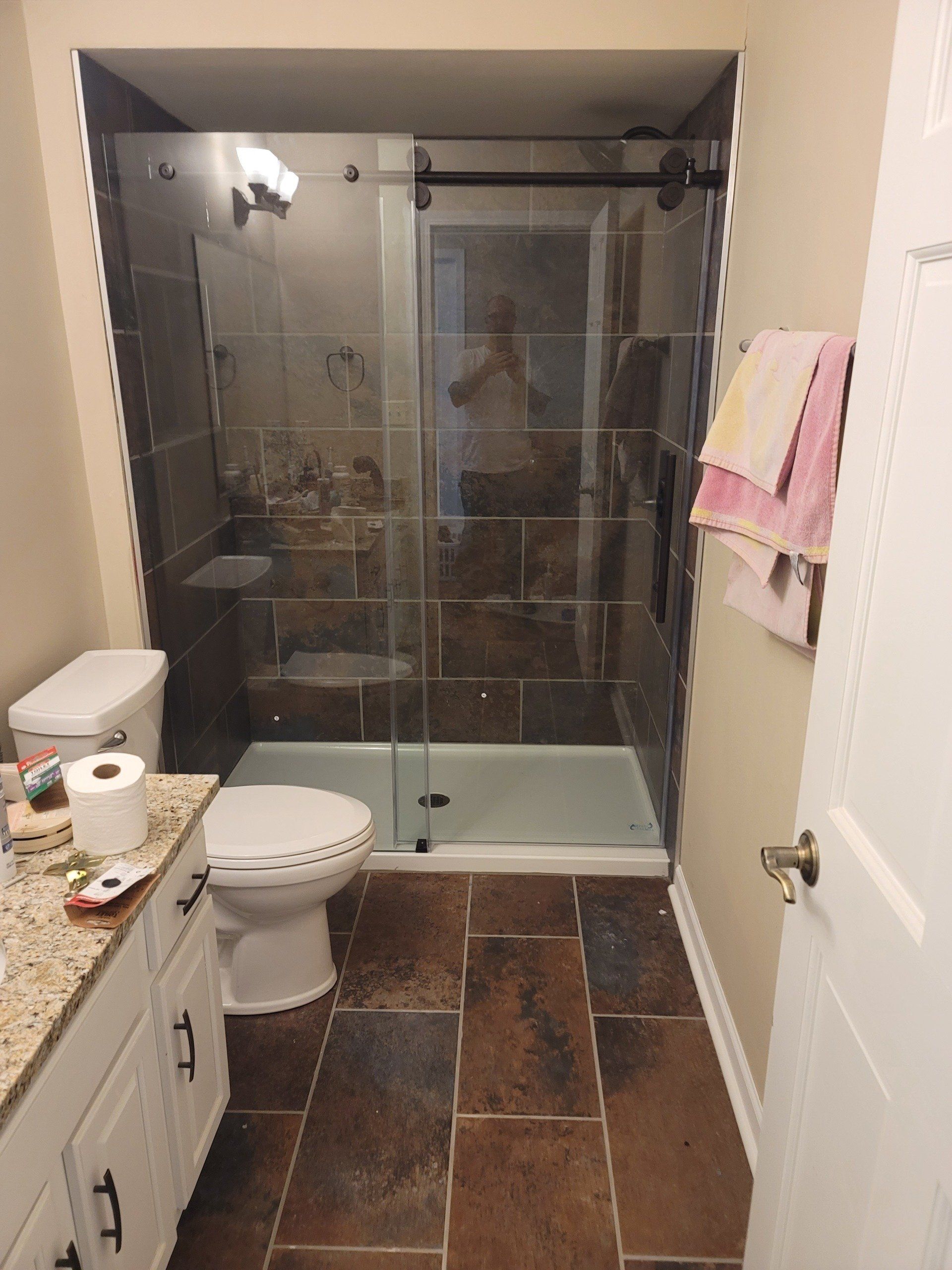 A bathroom with a toilet , sink and shower.