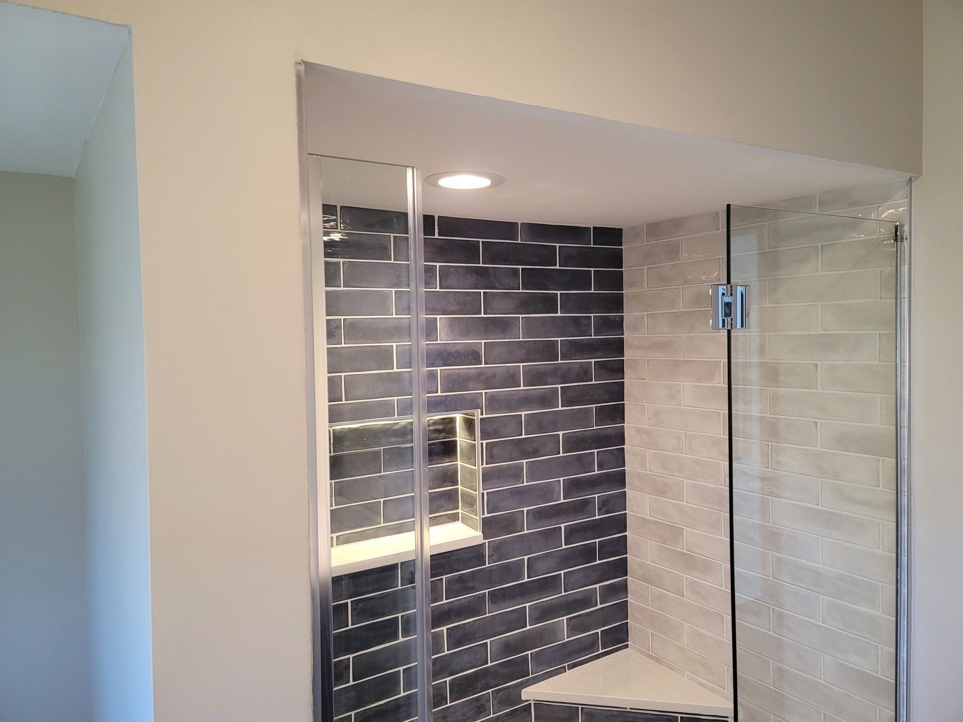 A bathroom with black and white tiles and a walk in shower with a glass door.