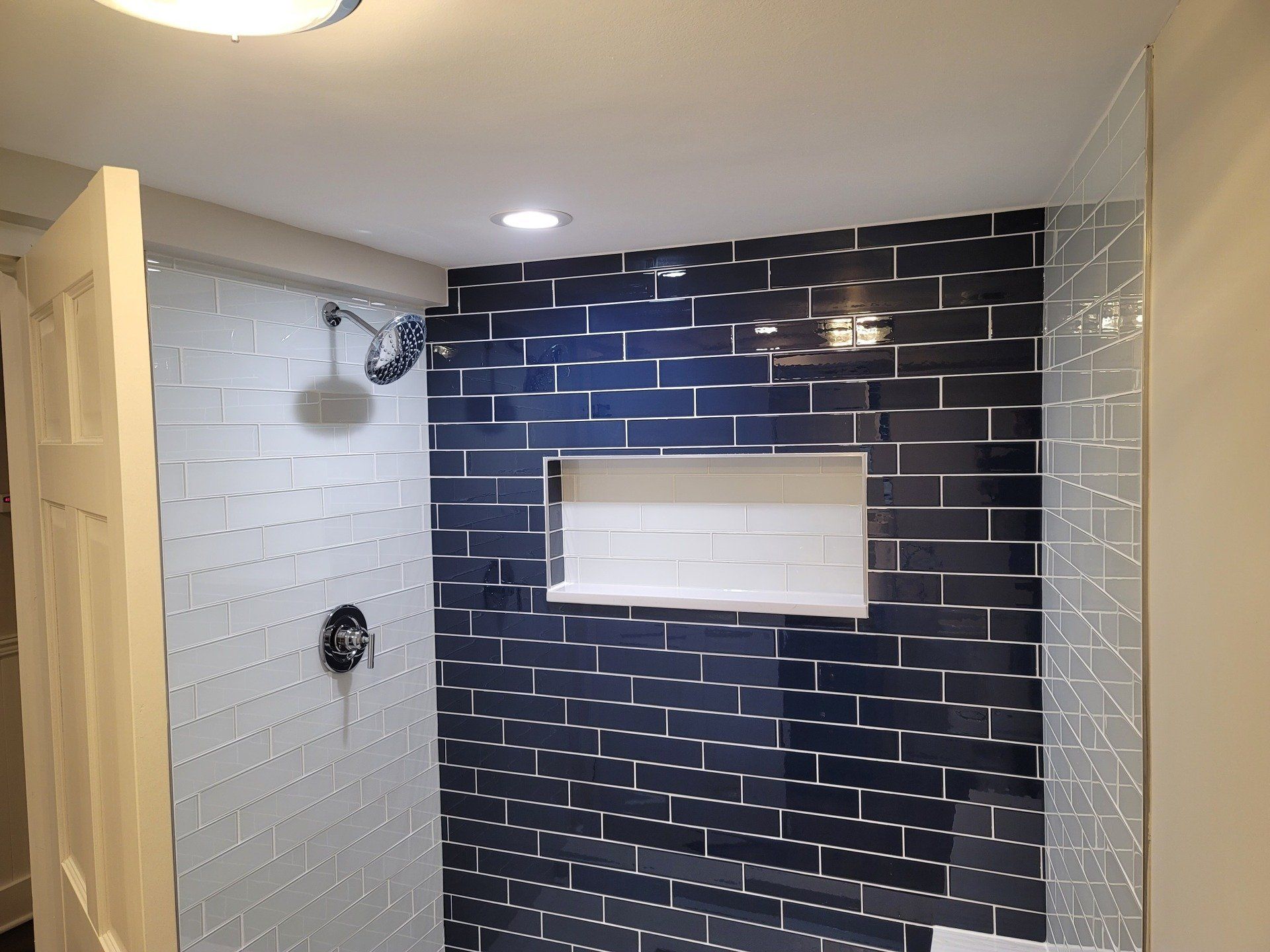 A bathroom with blue and white tiles and a shower stall.