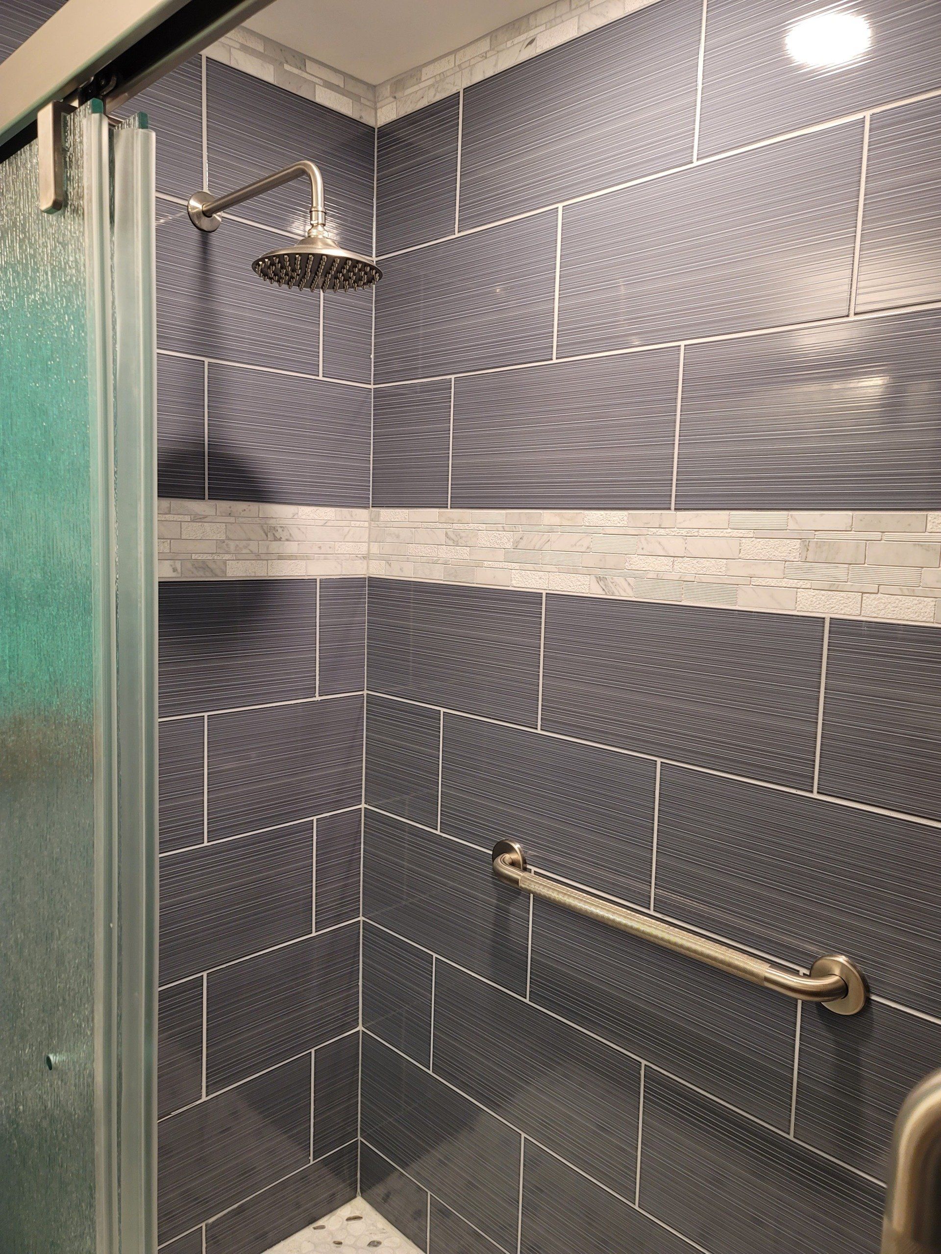 A shower with a sliding glass door and a shower head.