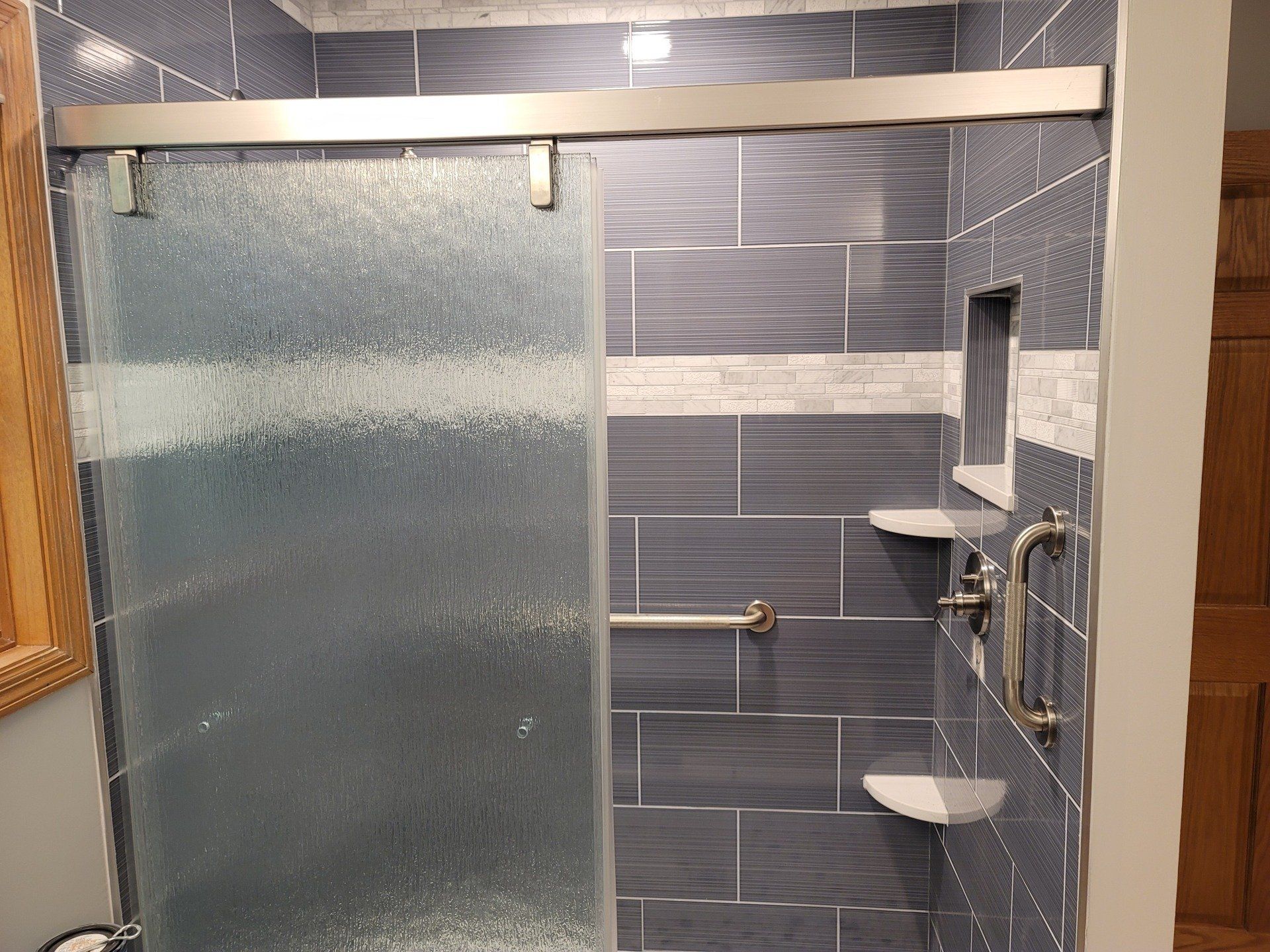 A bathroom with blue tiles and a sliding glass shower door.