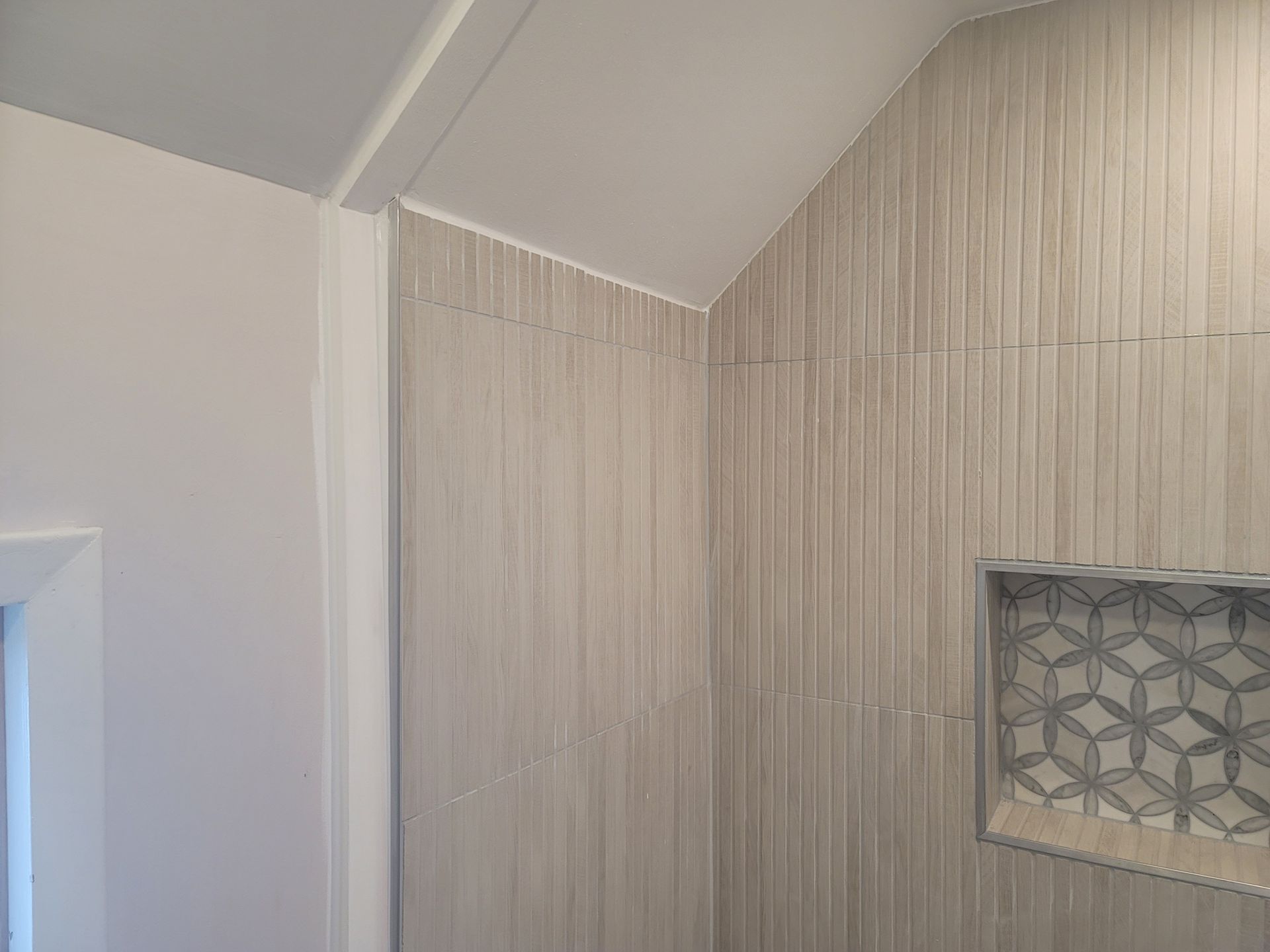A bathroom with a tiled wall and a niche in the shower.