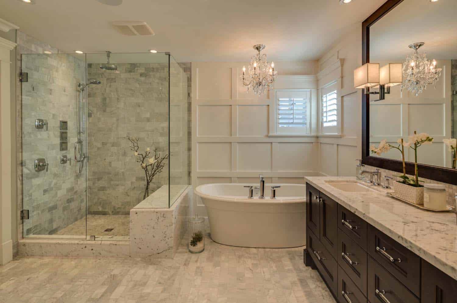 Elegant white bathroom with marble shower, soaking tub, and dark wood vanity.