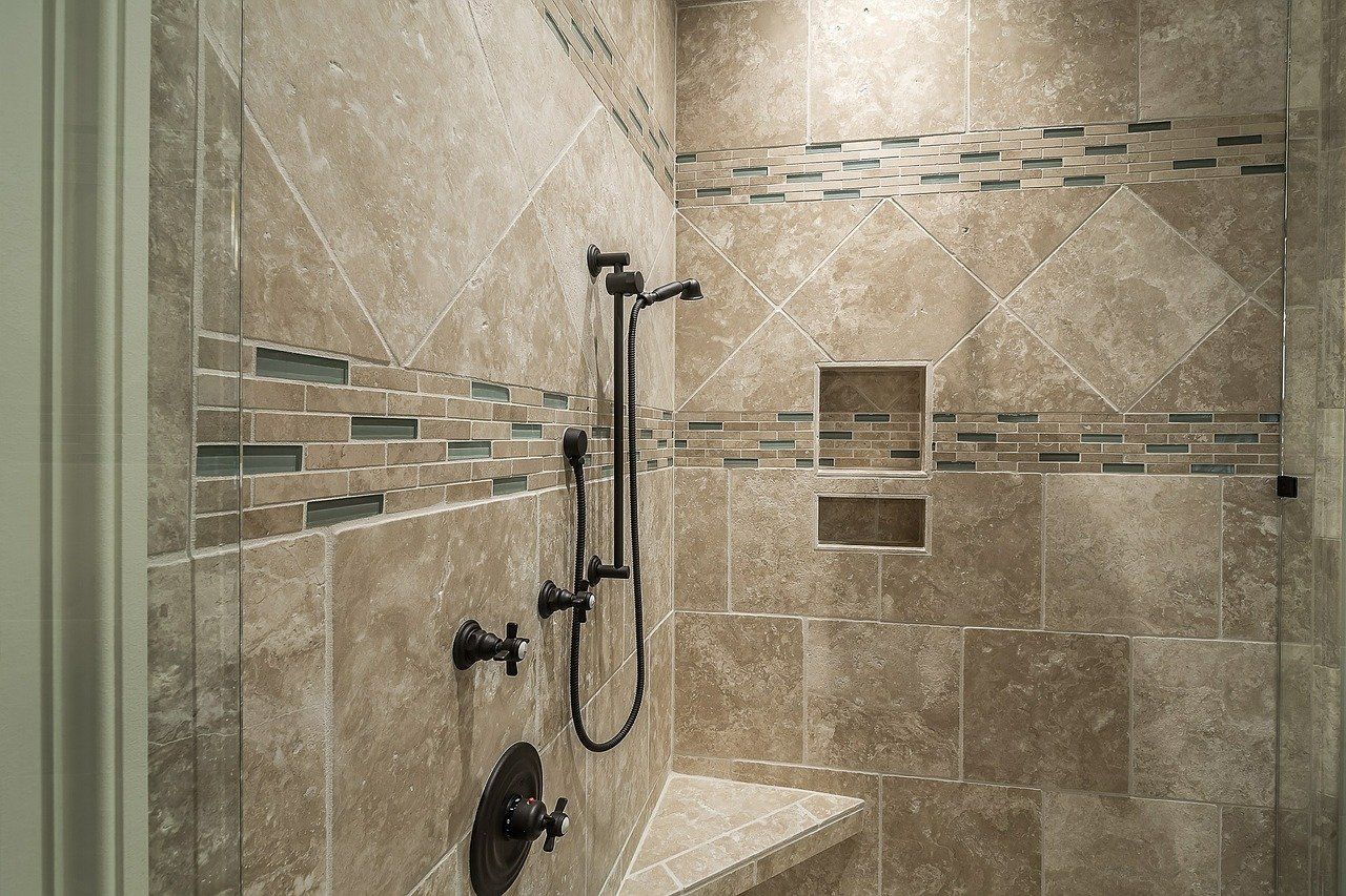 Tiled shower with dark fixtures and built-in bench. Features decorative mosaic band, two recessed shelves.