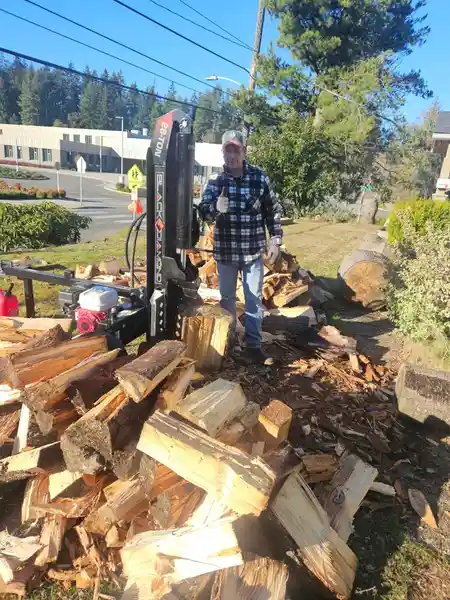 A man is standing next to a pile of wood.