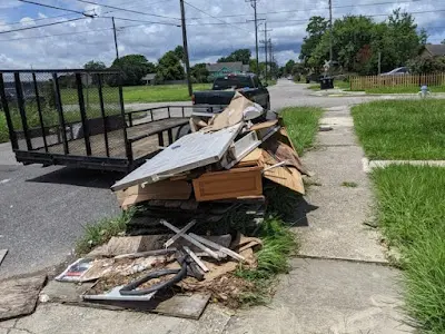 A pile of trash is sitting on the sidewalk next to a trailer.