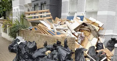 A pile of trash is sitting on the side of the road in front of a building.