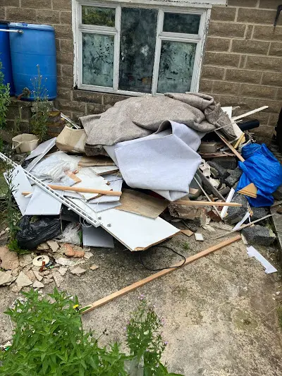 A pile of trash is sitting in front of a brick building.