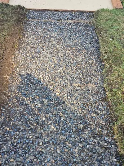 A gravel path is being built next to a grassy area.