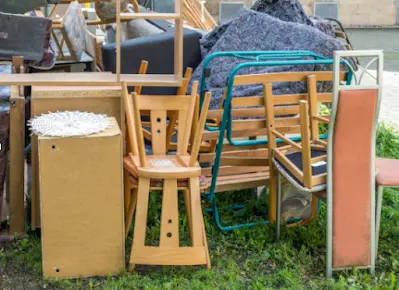 A pile of furniture is sitting on top of a lush green field.
