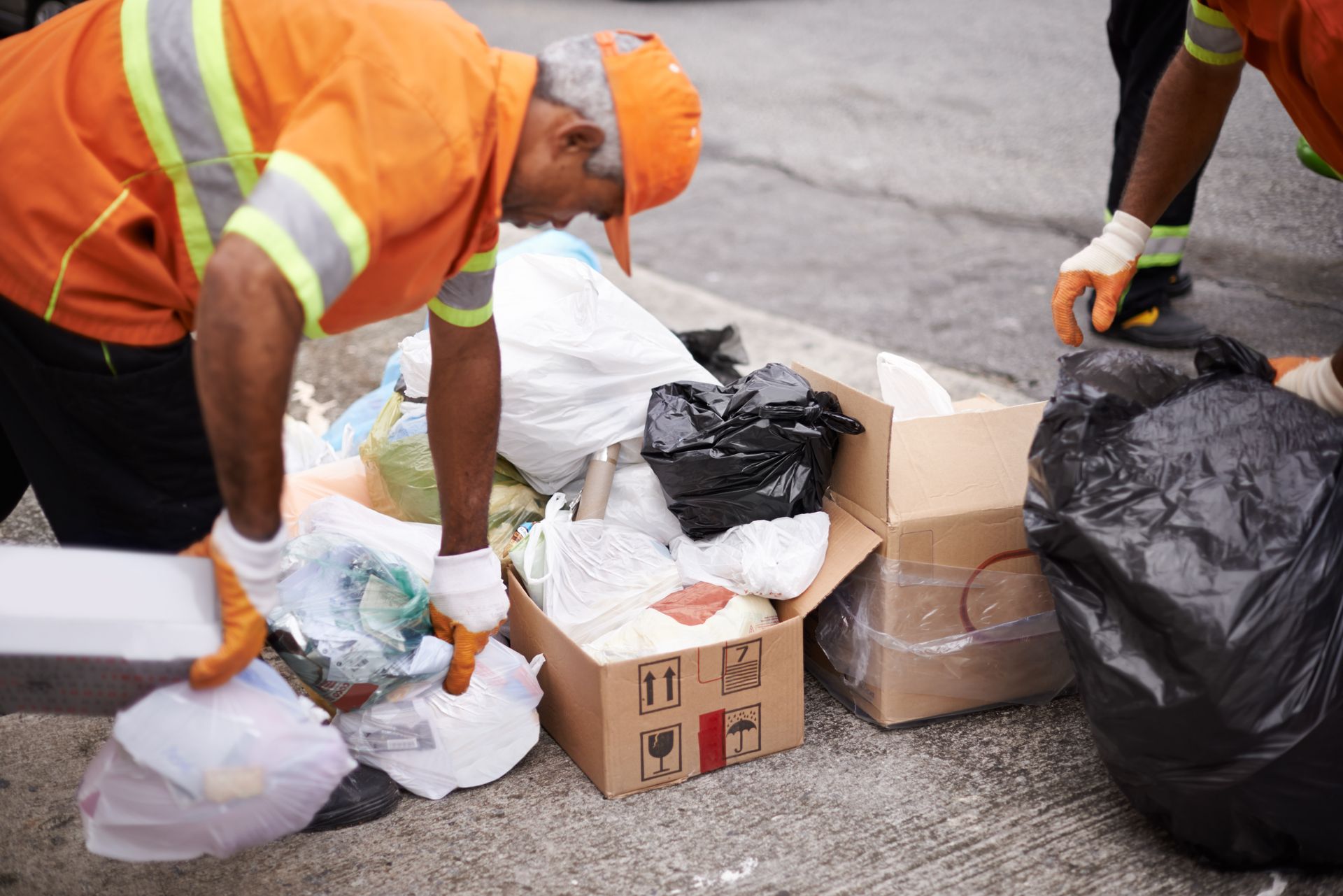 A man is kneeling down next to a pile of trash.
