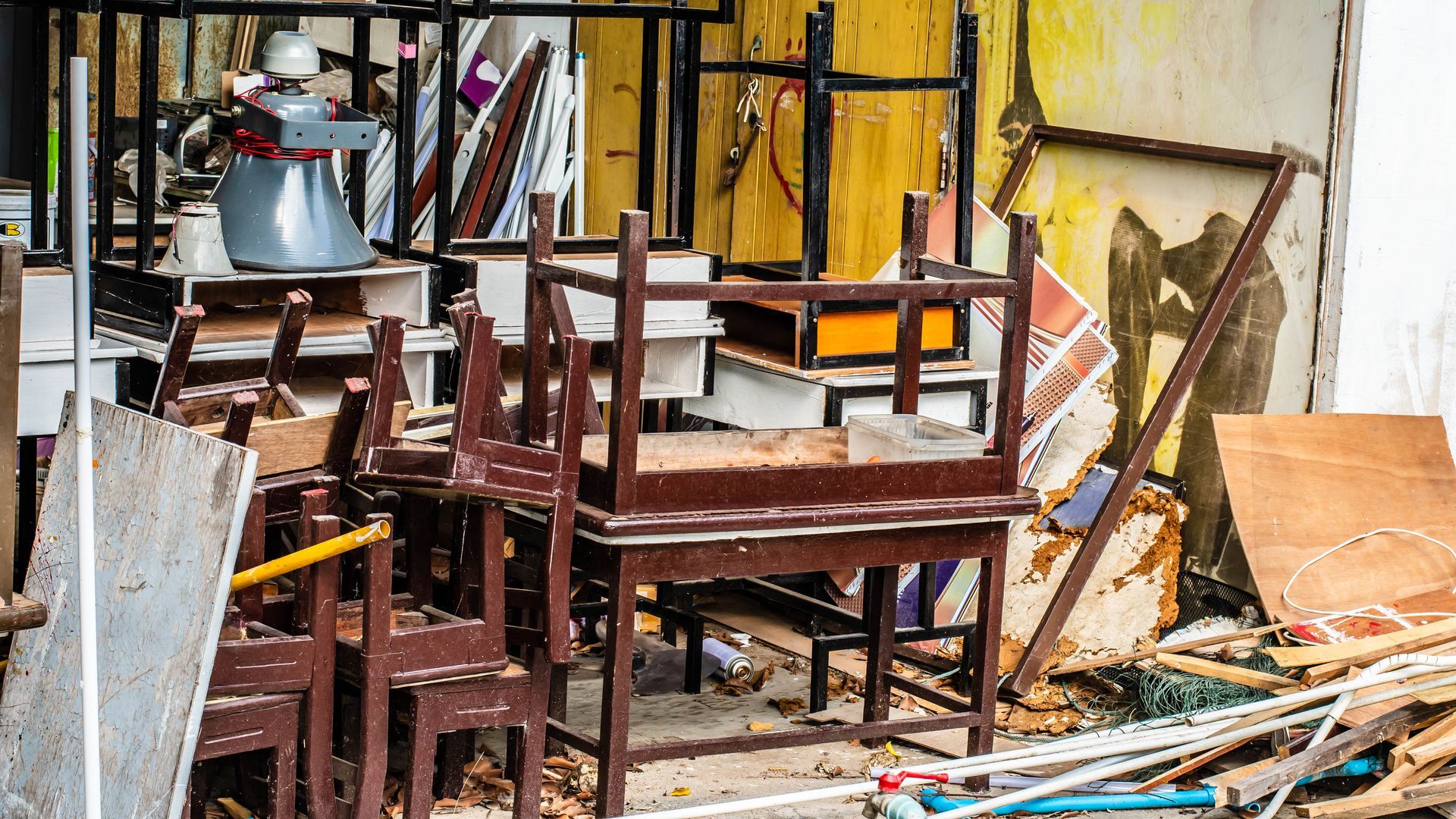 A pile of wooden chairs and tables in a room.
