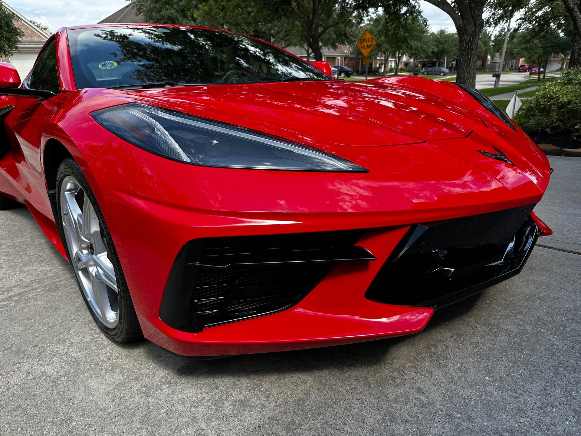 A black car with the hood up is parked in a field