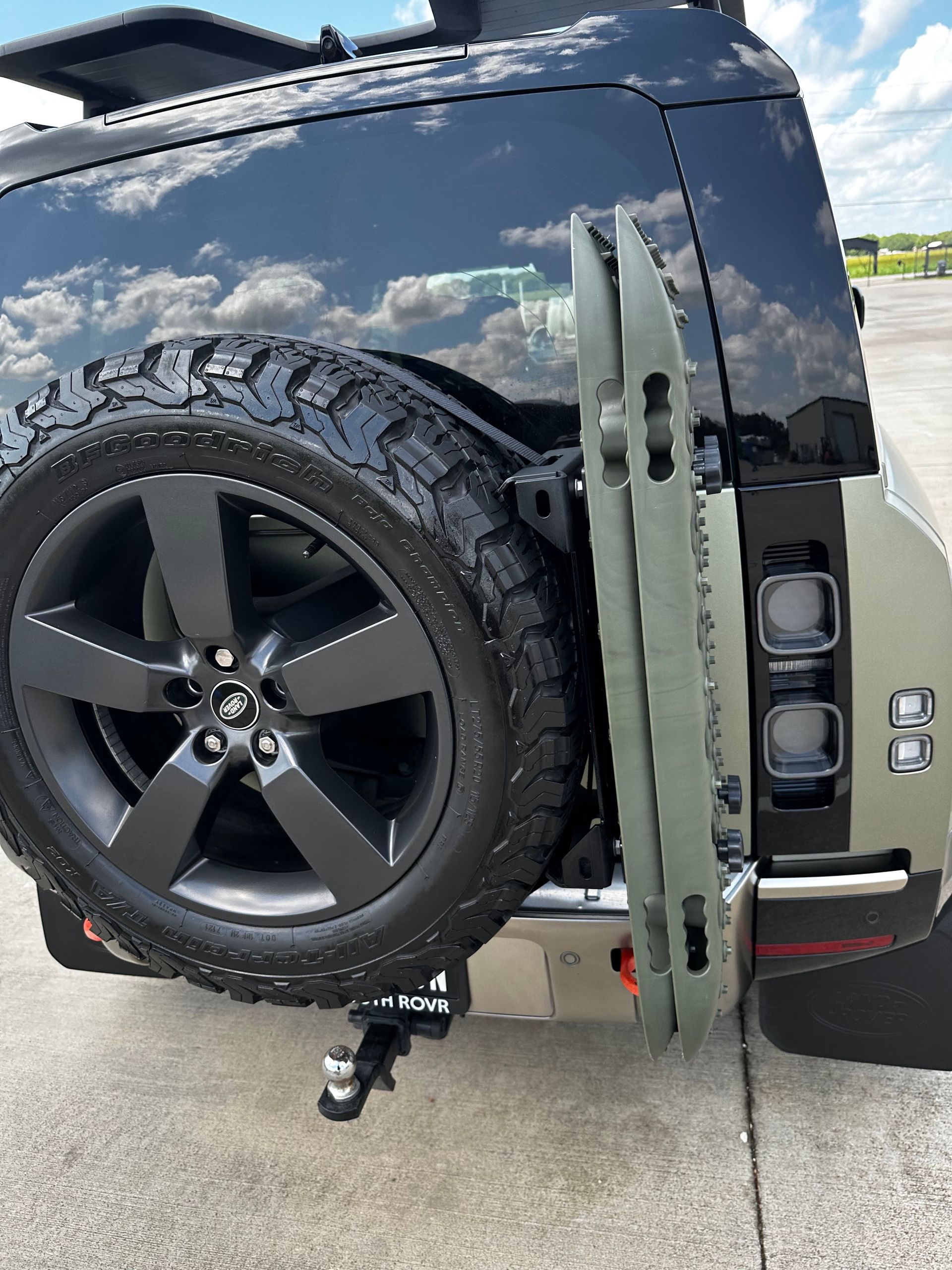 A black land rover defender with a spare tire attached to the back of it.