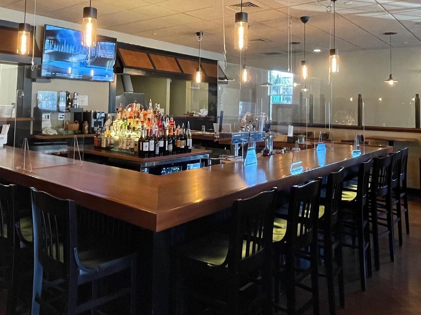 A long bar in a restaurant with a lot of bottles on it