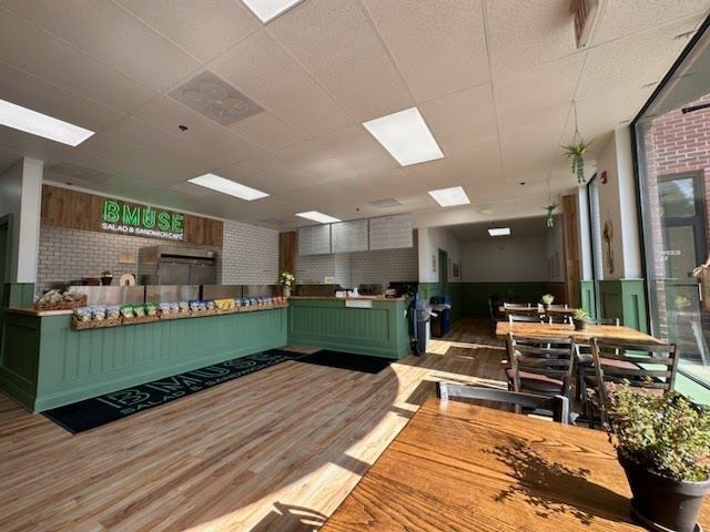 A restaurant with tables and chairs and a green counter.