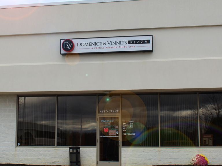 A white building with a sign that says dominics & vinnies