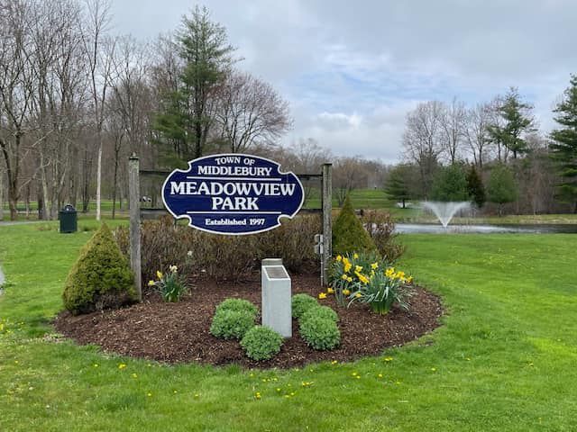 A sign for meadowview park is in the middle of a lush green field