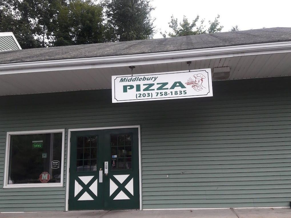 A green building with a sign that says middlebury pizza