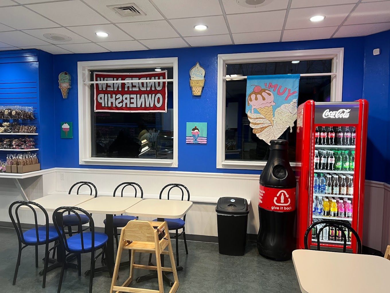 A restaurant with tables and chairs and a coca cola fridge
