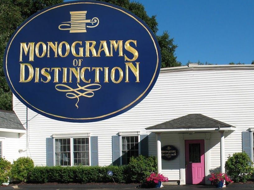 A white building with a blue sign that says monograms of distinction