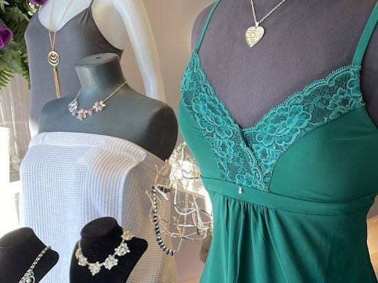 A green dress is on a mannequin next to a white dress
