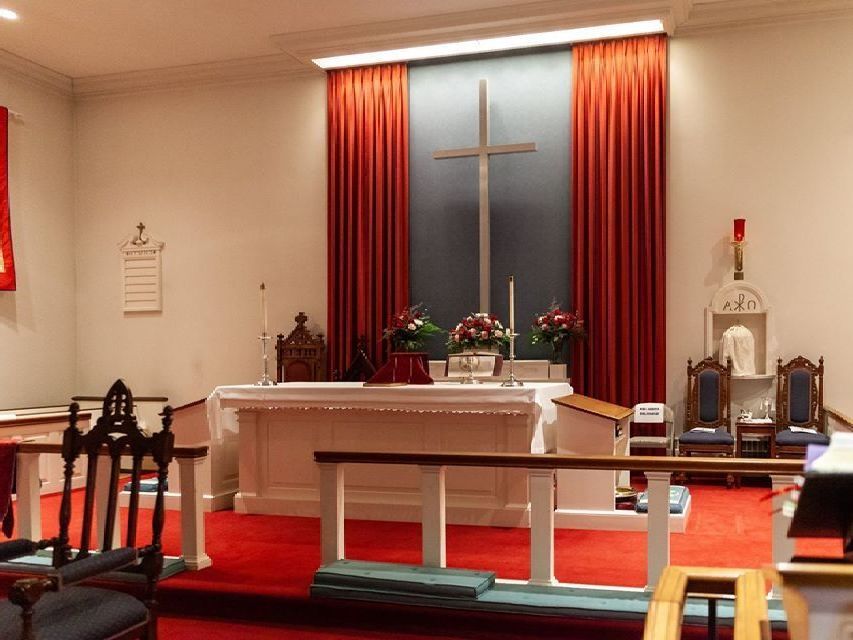 A church with a cross on the altar and red curtains