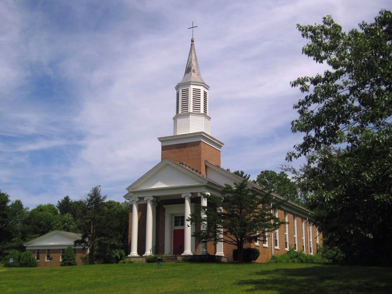 A brick church with a steeple and a cross on top